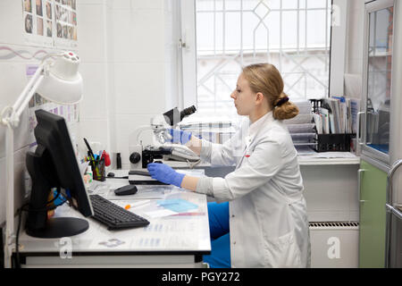 Doctor woman working with a microscope in Laboratory. Female scientist looking through a microscope in lab. Scientist using a microscope in a laboratory. Stock Photo