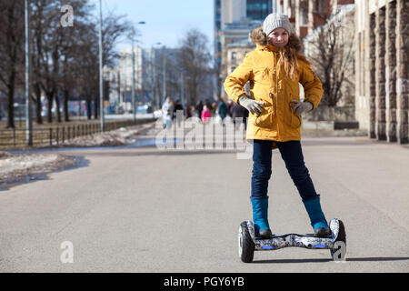 Happy young girl standing on self balanced vehicle on street pathway, copy-space Stock Photo