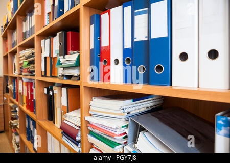 Row of colourful office folders with blank white labels on shelf Stock Photo