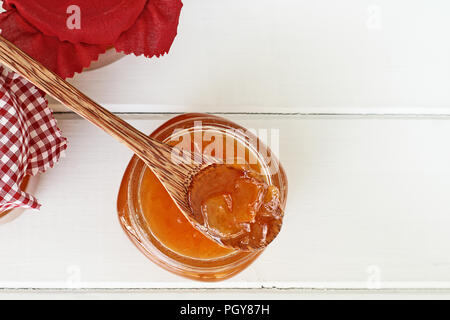 Overhead shot of a wooden spoon full of homemade Cantaloupe Jam resting in an open jar filled with jam. Shallow depth of field with selective focus. Stock Photo
