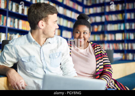 Cheerful African female student talking with her friend at library Stock Photo