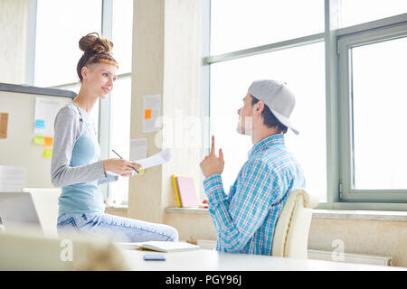 Positive hipster colleagues discussing company development and offering creative ideas while working in modern office Stock Photo