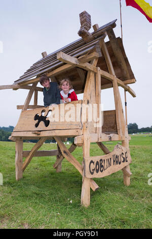 Chepstow, Wales – Aug 14: Two children peer out from the Goblin House wooden play house on 14 Aug 2015 at The Green Gathering Festival Stock Photo