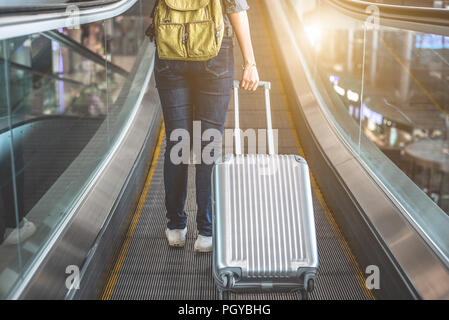 Back view of beauty woman traveling and holding suitcase on escalator in airport. People and Lifestyles concept. Travel around the world theme. Advent Stock Photo