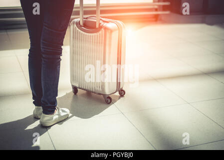 Close up woman and suitcase trolley luggage in airport. People and lifestyles concept. Travel and Business trip theme. Woman wearing jeans going on to Stock Photo