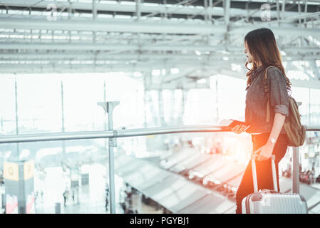 Beauty woman waiting for take off flight in airport. Asian woman with trolley suitcase. People and lifestyles concept. Transportation and Travel theme Stock Photo