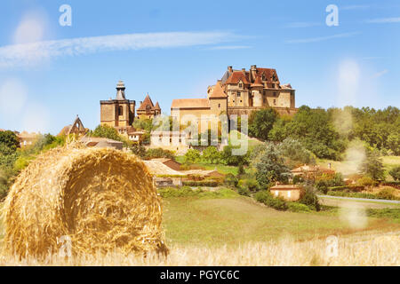 Beautiful view of Chateau de Biron ensemble with bale of hay in the foreground, France Stock Photo