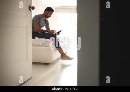 Hispanic Man Watching Movie On Tablet In Bed Stock Photo