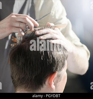 Man getting hair cut by scissor in barbershop. Barber use scissor and ...