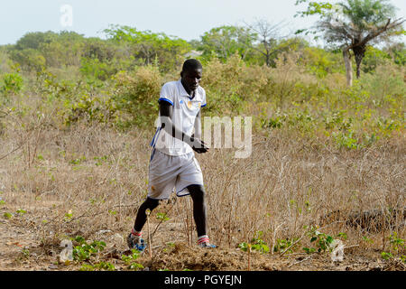 ORANGO ISLAND, GUINEA BISSAU - MAY 3, 2017: Unidentified local football player walks along the field after a physical culture lesson on the Orange isl Stock Photo