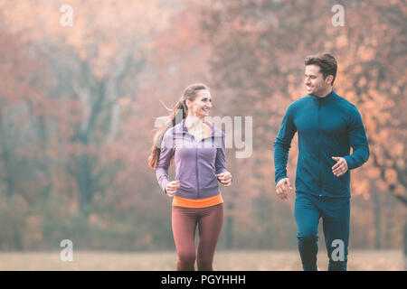 Couple in wonderful fall landscape running for better fitness towards the camera Stock Photo