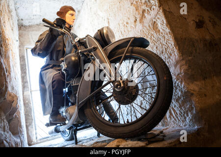 KURESSAARE, ESTONIA - CIRCA MAR, 2018: Ancient motorcycle with motorcyclist statue as driver. Showpiece is in Saaremaa museum in Kuressaare Castle. Wo Stock Photo
