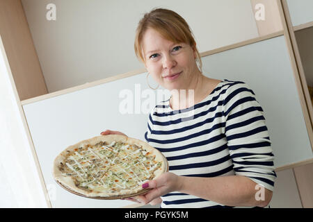 Happy smiling Caucasian woman holding pizza on plate Stock Photo
