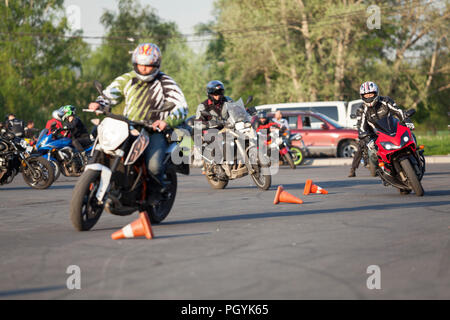 ST. PETERSBURG, RUSSIA-CIRCA MAY, 2018: Motorbikers riding through red cones on urban square. High-speed maneuvering. Free skill training as gymkhana  Stock Photo