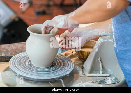 the Potter molds a pot from clay on a Potter's wheel. The master's hands make a pot on the potter's wheel Stock Photo