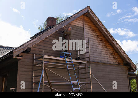 Senior man building a house by standing on scaffolding Stock Photo