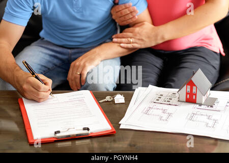 Young Couple Signing Loan Contract For House Purchasing Stock Photo