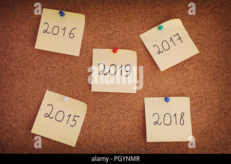 Adhesive notes with years from 2015 to 2019 on bulletin board. Close up. Stock Photo