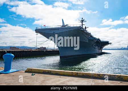 The USS Hornet, an aircraft carrier converted into a maritime museum, is visible moored on the West end of the Alameda, California, under a dramatic sky, with the urban skyline of San Francisco, California visible in the distance, May 14, 2018. () Stock Photo