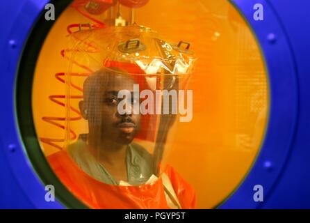 Photograph of a Center for Disease Control (CDC) Special Pathogens Branch staff microbiologist, wearing a safety suit, and peering through an airtight portal in the Biosafety Level 4 (BSL-4) laboratory decontamination shower, 2007. Image courtesy CDC/Dr Scott Smith. () Stock Photo