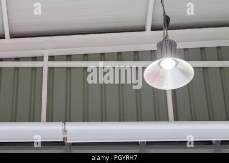 led light bulb in the industrial lamp is bright on the ceiling of the new warehouse with copy space, High Bay Lighting. Stock Photo