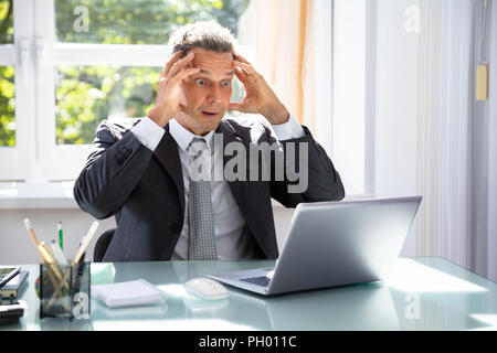 Shocked Mature Businessman Looking At Laptop Screen In Office Stock Photo