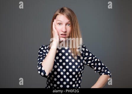 Shocked amazed female model with widely opened eyes, gestures in bewilderment, being in stupor. Stock Photo