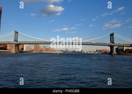 Manhattan bridge across East river in New York as seen from a boat under Brooklyn bridge Stock Photo