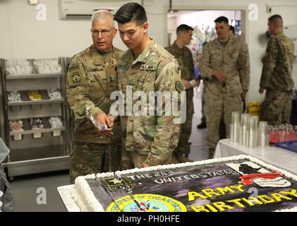 U.S. Army Master Sgt. Jeffrey Laws, Combined Joint Task Force – Operation Inherent Resolve and Pvt. Anthony San Nicolas, 3rd Cavalry Regiment, hold a cake cutting sword during the U.S. Army’s 243rd birthday ceremony, June 14, 2018, Union III, Baghdad, Iraq. The Army was established June 14, 1775, more than a year before the signing of the Declaration of Independence. Laws and Nicolas are the oldest and youngest soldiers at Union III respectively. Stock Photo