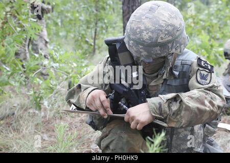 U.S. Army Reserve Spc. Nicolas Cholula, a combat documentation production specialist from Oxnard, California, with the 311th Signal Command (Theater Support Unit), plots his points to the first rally point during Land Navigation event at the 2018 U.S. Army Reserve Best Warrior Competition at Fort Bragg, North Carolina, June 14, 2018. Today, U.S. Army Reserve Soldiers give everything they have to push past their limits and finish the last day of events in the 2018 U.S. Army Reserve Best Warrior Competition. Stock Photo