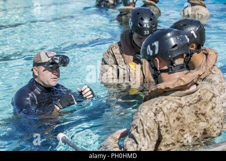 Joel Wismer, underwater egress training instructor, explains to Marines with 3rd Battalion, 5th Marine Regiment, how to employ their life vests underwater during underwater egress training at the Modular Amphibious Egress Trainer on Marine Corps Base Camp Pendleton, Calif., June 14, 2018. The hands-on training covered basic water safety, use of the equipment, and emergency procedures in the event of a crash into open waters. Stock Photo
