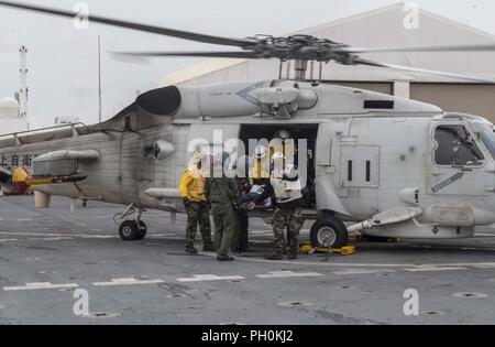 Japan (June 17, 2018) Sailors assigned to Military Sealift Command hospital ship USNS Mercy (T-AH 19) for Pacific Partnership 2018 (PP18) and Japanese Maritime Self-Defense Force (JMSDF) transfer a mock patient from an SH-60K Sea Hawk helicopter attached to the JMSDF during a bilateral medical training team drill between Mercy and JMSDF personnel. USNS Mercy is making port visits to Yokosuka and Tokyo to promote relationships between U.S. Navy Sailors and Japanese citizens through cultural exchange and bilateral training. Stock Photo