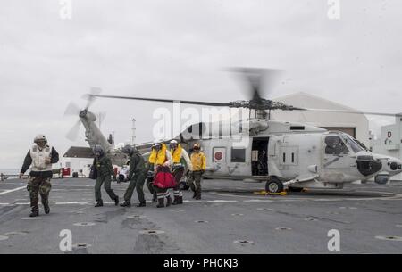 Japan (June 17, 2018) Sailors assigned to Military Sealift Command hospital ship USNS Mercy (T-AH 19) for Pacific Partnership 2018 (PP18) and Japanese Maritime Self-Defense Force (JMSDF) transfer a mock patient from an SH-60K Sea Hawk helicopter attached to the JMSDF during a bilateral medical training team drill between Mercy and JMSDF personnel. USNS Mercy is making port visits to Yokosuka and Tokyo to promote relationships between U.S. Navy Sailors and Japanese citizens through cultural exchange and bilateral training. Stock Photo