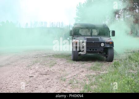 Green smoke simulates an improvised explosive device  during a Mass Casualty Training event in support of Golden Coyote, Custer State Park, S.D., June 16, 2018. The Golden Coyote exercise is a three-phase, scenario-driven exercise conducted in the Black Hills of South Dakota and Wyoming, which enables commanders to focus on mission essential task requirements, warrior tasks and battle drills. Stock Photo