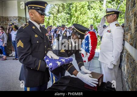 U.S. Navy Lt. Cmdr. Justin Callaghan, right, salutes as Sgt. Raheem Rowell, center, and Sgt. Bless Sherrill, both with the New Jersey Army National Guard, place an urn containing the cremains of a veteran and a flag during the 28th New Jersey Mission of Honor (NJMOH) ceremony at the Brigadier General William C. Doyle Veterans Memorial Cemetery at North Hanover Township, N.J., June 14, 2018. The cremains of seven World War II veterans Geoffrey N. Barrow, Henry Brandon and wife, Willa Mae; Arthur R. Callan, James Grant Sr., Theodore R. Jackson Jr., Monroe E. Morris, and Charlie Waters; two Vietn Stock Photo