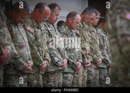 U.S. Army National Guard Soldiers assigned to B. Co., 935th Aviation Support Battalion (ASB), 35th Combat Aviation Brigade, bow their heads for the benediction after completing a shoulder-sleeve insignia, or patching, ceremony at North Fort Hood, Texas, June 15, 2018.  Capt. Harold Pence, a chaplain with Headquarters and Support Company, 935th ASB, conducted the invocation and benediction to honor Bravo company. Stock Photo