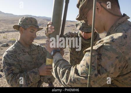 Lance Cpl. Andre Giordon (left) and Lance Cpl. Benjamin Strube (center), scout observers with Battery M, 3rd Battalion, 14th Marine Regiment, 4th Marine Division, and Cpl. Jonathan Azali (right), a radio operator with 3rd Air Naval Gunfire Liaison Company, Force Headquarters Group, begin configuring a Cobham COM201B low-band VHF antenna to establish communication for leaders of Company A, 1st Battalion, 23rd Marine Regiment, 4th MARDIV, during Integrated Training Exercise 4-18, aboard Marine Corps Air Ground Combat Center Twentynine Palms, Calif., June 17, 2018. ITX 4-18 provides Marine Air-Gr Stock Photo