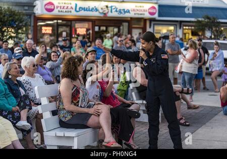 Tech. Sgt. Nalani Quintello, Max Impact vocalist, gives a high five to Gwennyth Farmer of Millsboro, Del., during the band’s performance June 16, 2018, on the bandstand at Rehoboth Beach, Del. Max Impact performed 20 songs for hundreds of beachgoers during the free, public concert. Max Impact, the premier rock band of the U.S. Air Force, is stationed at Joint Base Anacostia-Bolling in Washington, D.C. Stock Photo