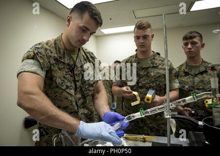 U.S. Marine Corps Cpl. Mitchell Waldon, left, Cpl. Austin Boland and Pfc. Cameron Rogers, chemical, biological, radiological, and nuclear (CBRN) defense specialists with CBRN Platoon, Headquarters Battalion, 1st Marine Division, practice sampling operations during the Concept of Real World CBRN Operations course at the Guardian Centers in Perry, Georgia, June 19, 2018. This training was conducted to enhance and refine the conduct of sensitive site exploitation, which supports the commander’s decision making cycle and maintains momentum during combat operations. Stock Photo