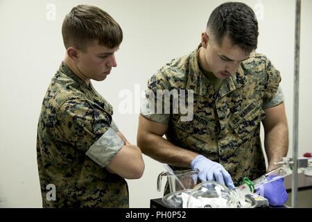 U.S. Marine Corps Cpl. Mitchell Waldon, left, and Pfc. Cameron Rogers, both chemical, biological, radiological, and nuclear (CBRN) defense specialists with CBRN Platoon, Headquarters Battalion, 1st Marine Division, practice sampling operations during the Concept of Real World CBRN Operations course at the Guardian Centers in Perry, Georgia, June 19, 2018. This training was conducted to enhance and refine the conduct of sensitive site exploitation, which supports the commander’s decision making cycle and maintains momentum during combat operations. Stock Photo