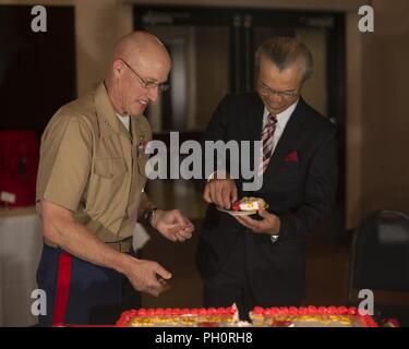U.S. Marine Corps Col. Richard F. Fuerst, commanding officer of Marine Corps Air Station (MCAS) Iwakuni, and Kosaku Morimoto, a master labor contractor with Station Facilities, share a piece of cake at MCAS Iwakuni, Japan, June 20, 2018. The cake was presented by Civilian Human Resources Office employees during a retirement ceremony for master labor contractors and individual hire agreement employees with the air station. Stock Photo