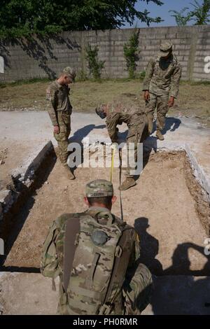 U.S. Army Paratroopers assigned to Bravo Company, 54th Brigade Engineer Battalion, 173rd Airborne Brigade, measure the crater during  light airfield repair and crater repair training with the High Mobility Engineer Excavator (HMEE) near Trecenta , Rovigo, June 20, 2018. The 173rd Airborne Brigade, based in Vicenza, Italy, is the U.S. Army Contingency Response Force in Europe, capable of projecting forces to conduct the full range of military operations across the United States European, Central and Africa Commands areas of responsibility. Stock Photo