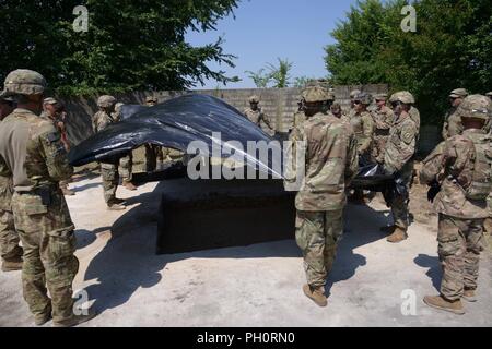 U.S. Army Paratroopers assigned to Bravo Company, 54th Brigade Engineer Battalion, 173rd Airborne Brigade, place the Waterproof sheet during the light airfield repair and crater repair training with the High Mobility Engineer Excavator (HMEE) near Trecenta , Rovigo, June  20, 2018. The 173rd Airborne Brigade, based in Vicenza, Italy, is the U.S. Army Contingency Response Force in Europe, capable of projecting forces to conduct the full range of military operations across the United States European, Central and Africa Commands areas of responsibility. Stock Photo