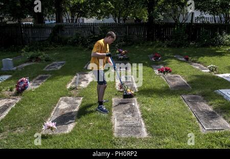 VIRGINIA BEACH, Va. (June 18, 2018) Hull Technician 3rd Class Dwayne Costa, from Grove City, Ohio, assigned to the aircraft carrier USS George H.W. Bush (CVN 77) clears debris from headstones at Jones Memorial Park in Virginia Beach, Virginia during a community relations project.  As a birthday tribute to the ship's namesake, and representing his famous 'Thousand Points of Light' speech, approximately 1,000 GHWB crew members took part in one of the largest single-day community relation (COMREL) events at 44 different locations throughout the Hampton Roads area. George H.W. Bush turned 94 on Ju Stock Photo