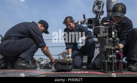 SEA (June 21, 2018) Gunner's Mate 3rd Class Alexander Harrison, left, Gunner's Mate 2nd Class Alyssia Faifili, center, and Gunner's Mate 2nd Class Kyle Breese complete preventative maintenance on a Mark 38 machine gun aboard the Harpers Ferry-class dock landing ship USS Oak Hill (LSD 51), June 21, 2018. Oak Hill, homeported in Virginia Beach, Virginia, is conducting naval operations in the U.S. 6th Fleet area of operations. Stock Photo