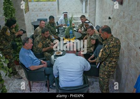 U.S. Army Gen. Joseph Votel, Central Command commander, John Rood, Under Secretary of Defense for Policy, Maj. Gen. Jaime Jarrard, Special Operations Joint Task Force – Operation Inherent Resolve commander, Lt. Gen. Paul Funk, Combined Joint Task Force – Operation Inherent Resolve commander, and leaders from the Syrian Democratic Forces speak with a local shop owner in Manbij, Syria, June 21, 2018. This engagement was part of a tour of the city for the leaders to see how safe and prosperous the city has become since the SDF eliminated ISIS from the area. Stock Photo