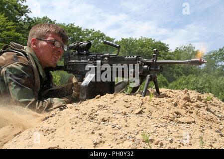 Spc. Colton Kutchmark, a machine gunner with Company C, 1-148th Infantry Regiment and a Toronto, Ohio native, kicks up sand with the shell casings of the simulated rounds ejecting from his M240B macine gun while replicating an opposing forces ambush during tactical convoy operations training June 21 at the Camp Grayling Joint Maneuver Training Center in Grayling, Mich. The real-world scenario is two-fold, allowing soldiers from both sides to build on their knowledge and skills, which increases their abilities to deploy for combat operations more quickly. Stock Photo