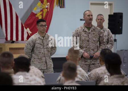 UNDISCLOSED LOCATION, MIDDLE EAST – U.S. Marine Corps Gunnery Sgt. Thomas Rogato (right), the maintenance chief for Combat Logistics Detachment 37, praises Cpl. Noah Pascual (left), a maintenance management specialist, for his excellence in the workplace during a town hall meeting with Special Purpose Marine Air-Ground Task Force, Crisis Response-Central Command June 22, 2018.  Pascual later received a coin from Lt. Gen. William D. Beydler, the commander of U.S. Marine Corps Forces Central Command. Stock Photo