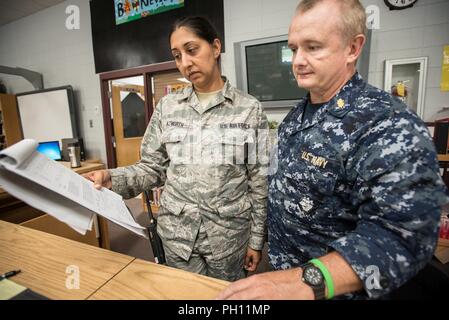 U.S. Air Force Master Sgt. Nikki Nazworth (left), from the Kentucky Air National Guard’s 123rd Airlift Wing, discusses patient care with U.S. Navy Lt. Cmdr. Frank McKeown, a registered nurse from Expeditionary Medical Facility Bethesda in Maryland, at a health-care clinic being run by the Air Guard and U.S. Navy Reserve at Owsley County High School in Booneville, Ky., June 20, 2018. The clinic is one of four that comprised Operation Bobcat, a 10-day mission to provide military medical troops with crucial training in field operations and logistics while offering no-cost health care to the resid Stock Photo