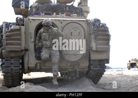 An Army Soldier with 1st Squadron, 7th Cavalry Regiment, 1st Armored Brigade Combat Team, 1st Cavalry Division, dismounts from an M3 Bradley Fighting Vehicle during a situational training exercise at Tactical Exercise Strip Joanna, Zagan, Poland, June 20, 2018. Garryowen Soldiers are currently deployed in support of Atlantic Resolve in Europe. Stock Photo